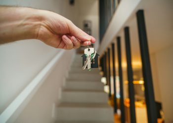 Here's a possible caption: keys being held in front of a staircase.