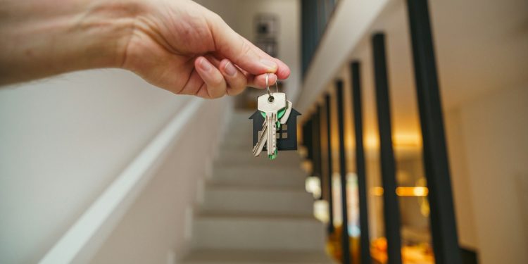 Here's a possible caption: keys being held in front of a staircase.